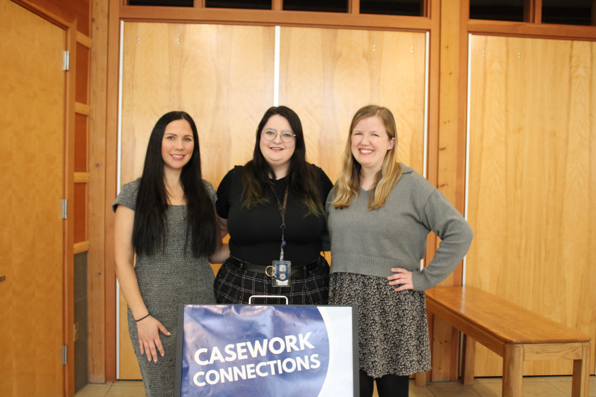Picture of 3 women smiling in front of a sign 